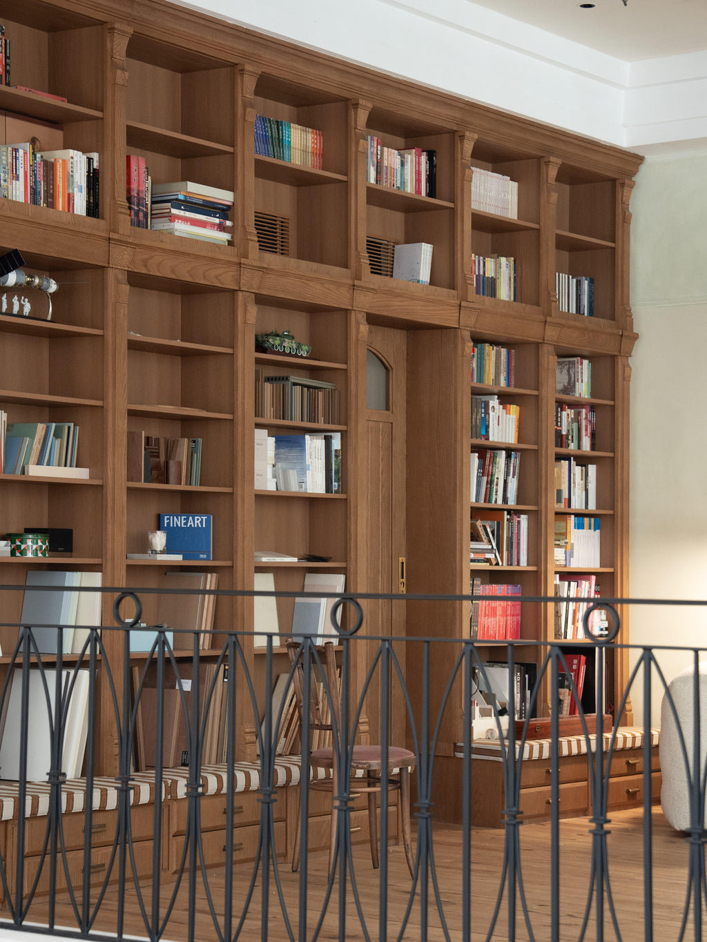 Custom Oak Veneer Library Wall with Integrated Door & Bench Seating